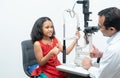 little cute Indian girl child patient is getting eyes exam from professional ophthalmologist or optometrist man at clinic Royalty Free Stock Photo