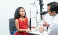 little cute Indian girl child patient is getting eyes exam from professional ophthalmologist or optometrist man at optometry clini Royalty Free Stock Photo