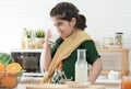 Little cute Indian kid girl holding and drinking a glass of milk for breakfast with bread, jam, crackers and fruits in kitchen Royalty Free Stock Photo