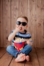 Little cute kid baby boy 2-3 years old , 3d cinema glasses holding bucket for popcorn, eating fast food on wooden background. Kids