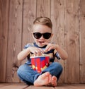 Little cute kid baby boy 2-3 years old , 3d imax cinema glasses holding bucket for popcorn, eating fast food on wooden background Royalty Free Stock Photo