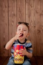 Little cute kid baby boy 2-3 years old , 3d imax cinema glasses holding bucket for popcorn, eating fast food on wooden background Royalty Free Stock Photo