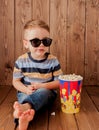 Little cute kid baby boy 2-3 years old , 3d imax cinema glasses holding bucket for popcorn, eating fast food on wooden background Royalty Free Stock Photo