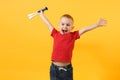 Little cute kid baby boy 3-4 years old, football fan in red t-shirt holding in hand pipe, blowing isolated on yellow Royalty Free Stock Photo