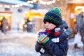 Little cute kid boy drinking hot children punch or chocolate on German Christmas market. Happy child on traditional Royalty Free Stock Photo