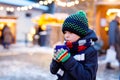 Little cute kid boy drinking hot children punch or chocolate on German Christmas market. Happy child on traditional Royalty Free Stock Photo