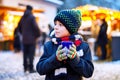 Little cute kid boy drinking hot children punch or chocolate on German Christmas market. Happy child on traditional Royalty Free Stock Photo