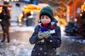 Little cute kid boy drinking hot children punch or chocolate on German Christmas market. Happy child on traditional Royalty Free Stock Photo