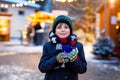 Little cute kid boy drinking hot children punch or chocolate on German Christmas market. Happy child on traditional Royalty Free Stock Photo