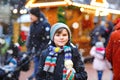 Little cute kid boy eating white chocolate covered fruit apple on skewer on traditional German Christmas market. Happy Royalty Free Stock Photo