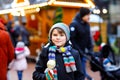 Little cute kid boy eating white chocolate covered fruit apple on skewer on traditional German Christmas market. Happy Royalty Free Stock Photo