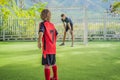 Little cute kid boy in red football uniform and his trainer or father playing soccer, football on field, outdoors Royalty Free Stock Photo