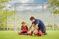 Little cute kid boy in red football uniform and his trainer or father playing soccer, football on field, outdoors Royalty Free Stock Photo