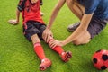 Little cute kid boy in red football uniform and his trainer or father playing soccer, football on field, outdoors Royalty Free Stock Photo