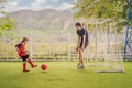 Little cute kid boy in red football uniform and his trainer or father playing soccer, football on field, outdoors Royalty Free Stock Photo