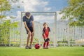 Little cute kid boy in red football uniform and his trainer or father playing soccer, football on field, outdoors Royalty Free Stock Photo