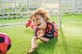 Little cute kid boy in red football uniform playing soccer, football on field, outdoors. Active child making sports with Royalty Free Stock Photo