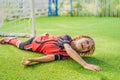 Little cute kid boy in red football uniform playing soccer, football on field, outdoors. Active child making sports with Royalty Free Stock Photo