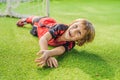 Little cute kid boy in red football uniform playing soccer, football on field, outdoors. Active child making sports with Royalty Free Stock Photo