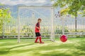 Little cute kid boy in red football uniform playing soccer, football on field, outdoors. Active child making sports with Royalty Free Stock Photo