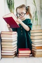 Little cute kid girl in glasses with pile of books, vertical