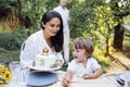 Little cute kid and his parents are tasting festive cake outdoors in garden Royalty Free Stock Photo