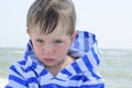 Little cute kid hurt and pouted, disappointed. Beautiful little kid with atopic dermatitis on the background of the sea,