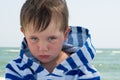 Little cute kid hurt and pouted, disappointed. Beautiful little kid with atopic dermatitis on the background of the sea,