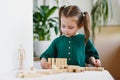 Little cute preschool girl plays at home with wood toys on table. Natural tactility development Royalty Free Stock Photo
