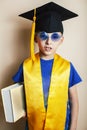 Little cute preschooler boy in glasses with books at home education in graduate hat smiling posing emotional, lifestyle Royalty Free Stock Photo