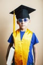 Little cute preschooler boy in glasses with books at home education in graduate hat smiling posing emotional, lifestyle Royalty Free Stock Photo