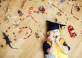 Little cute preschooler boy among toys lego at home education in graduate hat smiling posing emotional, lifestyle people Royalty Free Stock Photo