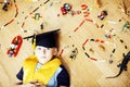 Little cute preschooler boy among toys lego at home in graduate hat smiling posing emotional, lifestyle people concept Royalty Free Stock Photo