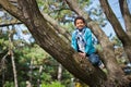 Little cute real black boy climbing on tree height