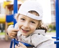 Little cute real boy playing on playground, hanging on gymnastic ring cheerful Royalty Free Stock Photo