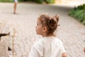 Little cute red-haired girl looks away in surprise while standing on a cobbled road Royalty Free Stock Photo