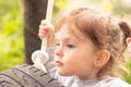 Little cute red-haired girl riding a black wheel swing tied with ropes on a hot summer day outdoors Royalty Free Stock Photo