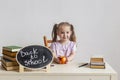 Little cute schoolgirl sits at her desk at school with textbooks.  Kid is learning in class. Back to school. Royalty Free Stock Photo