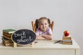 Little cute schoolgirl sits at her desk at school with textbooks.  Kid is learning in class. Back to school. Royalty Free Stock Photo