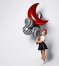 Schoolgirl in t-shirt, red headband, black skirt and sneakers. Holding balloons, posing isolated on white. Full length Royalty Free Stock Photo