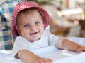 Little cute smiling girl in a hat sitting in a baby feeding chair, looking straight into the camera Royalty Free Stock Photo