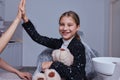 Little cute smiling girl is sitting in dental chair in clinic, office. Doctor is preparing for examination of child Royalty Free Stock Photo