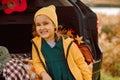 Little cute smiling girl standing near by on open car trunk. Kid resting with her family in the nature. Autumn season Royalty Free Stock Photo