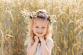 Little cute smiling girl with a wreath of flowers on her head in the summer in nature Royalty Free Stock Photo
