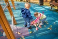 little cute toddler boy and a beautiful year-old baby girl in blue clothes play in a pink toy stroller for a doll in the