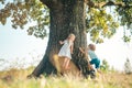 Little cute toddler boy and girl having fun and climbing on tree in summer forest. Children on a big tree. Royalty Free Stock Photo