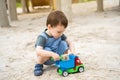 Little cute toddler boy 2.5 years old plays in the sandbox on a sunny summer day. Outdoor creative activities for kids. Toy car Royalty Free Stock Photo