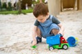 Little cute toddler boy 2.5 years old plays in the sandbox on a sunny summer day. Outdoor creative activities for kids. Toy car Royalty Free Stock Photo