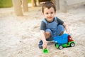 Little cute toddler boy 2.5 years old plays in the sandbox on a sunny summer day. Outdoor creative activities for kids. Toy car Royalty Free Stock Photo