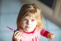 Little cute toddler girl making experiment with scissors and cutting hairs. Funny baby child cuts her pony herself at